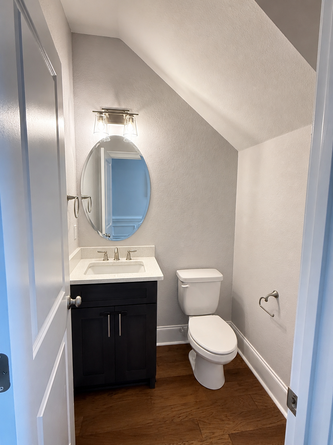 Half bath with vanity and toilet under a sloped ceiling
