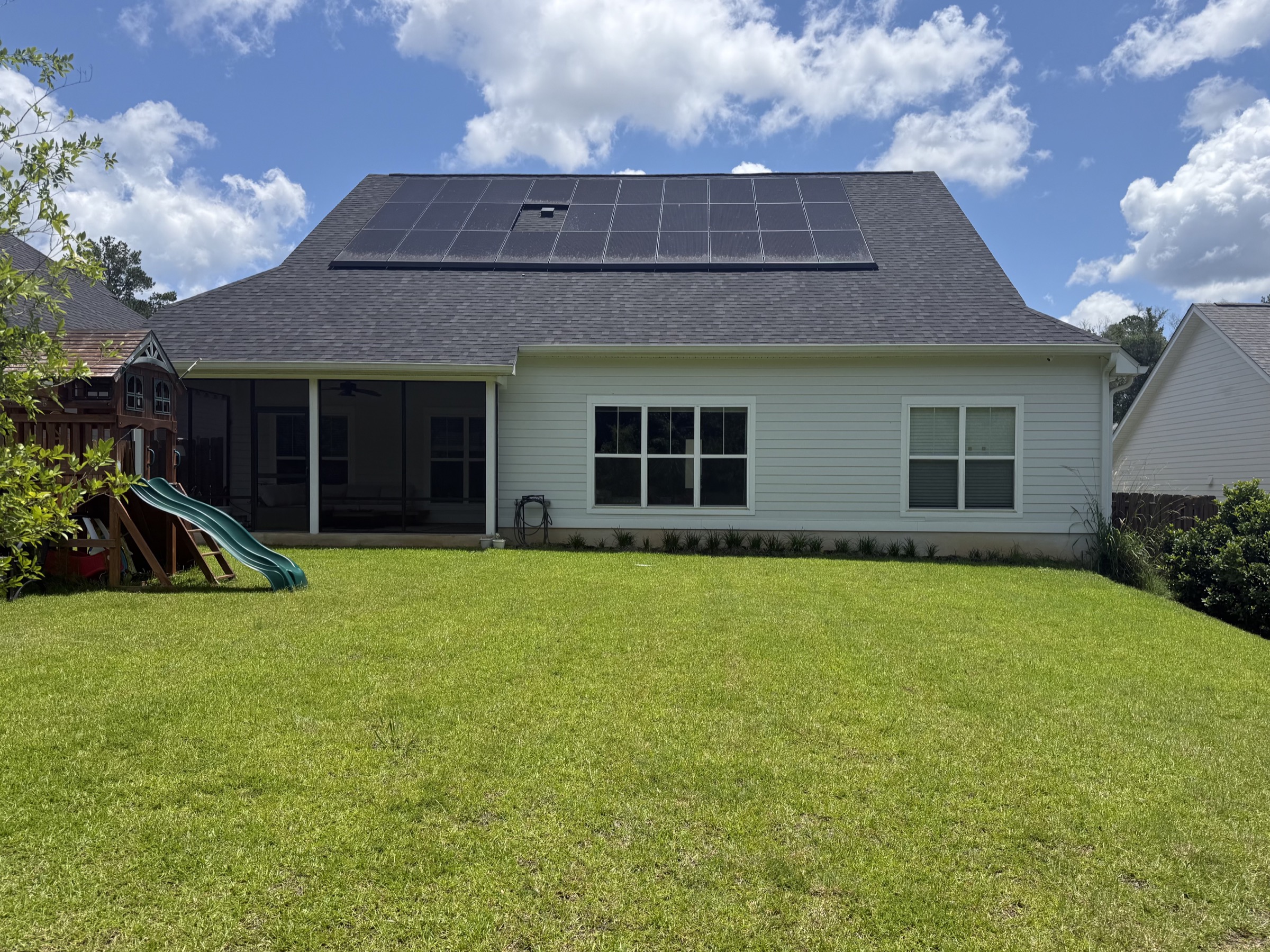 Backyard with green lawn, playset and solar panels